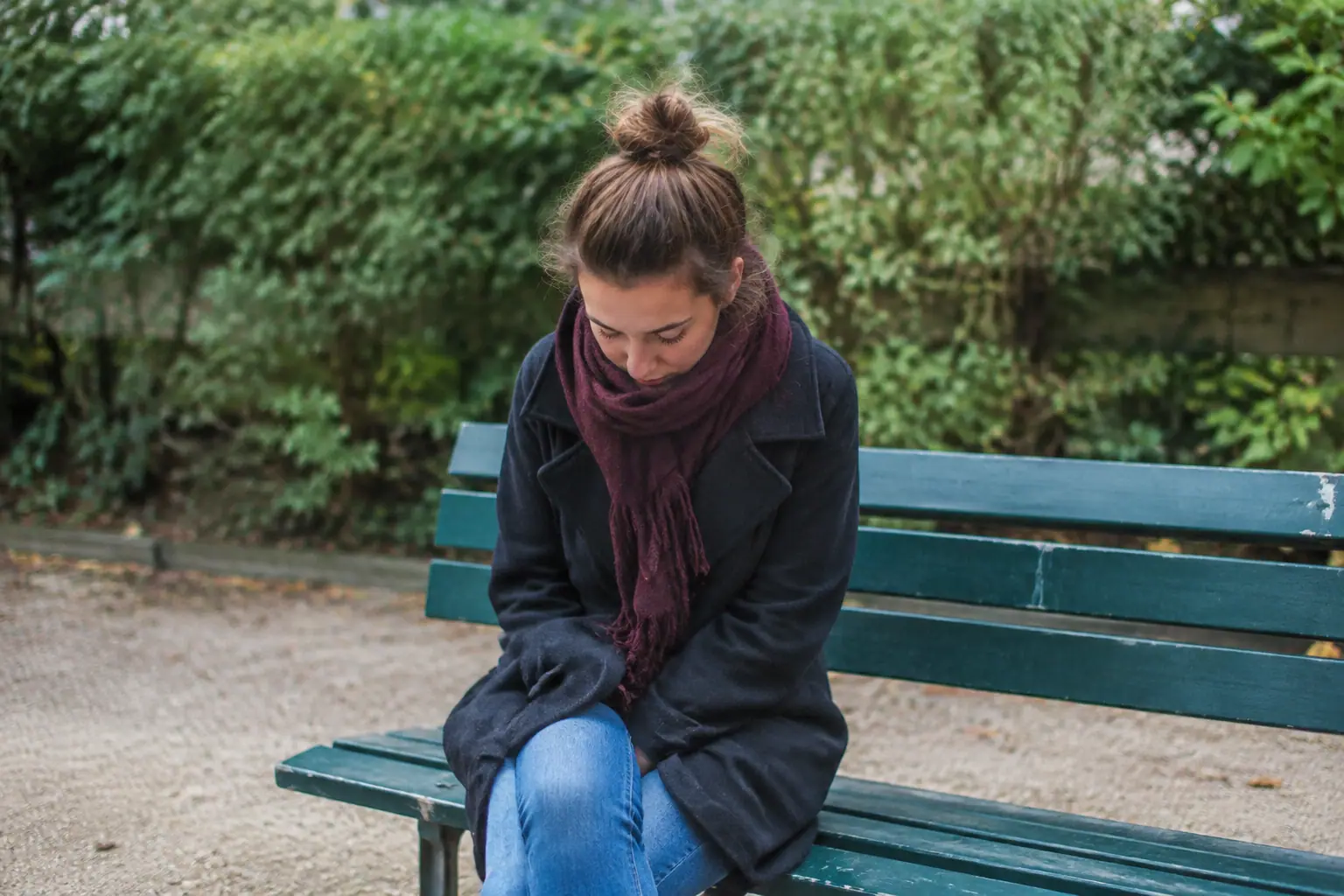 Femme assise seule sur un banc, tete baissee